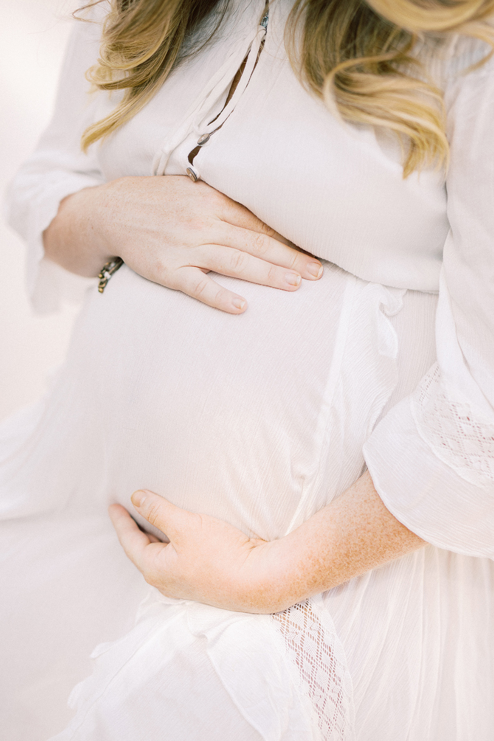 pregnant women holding belly in white dress