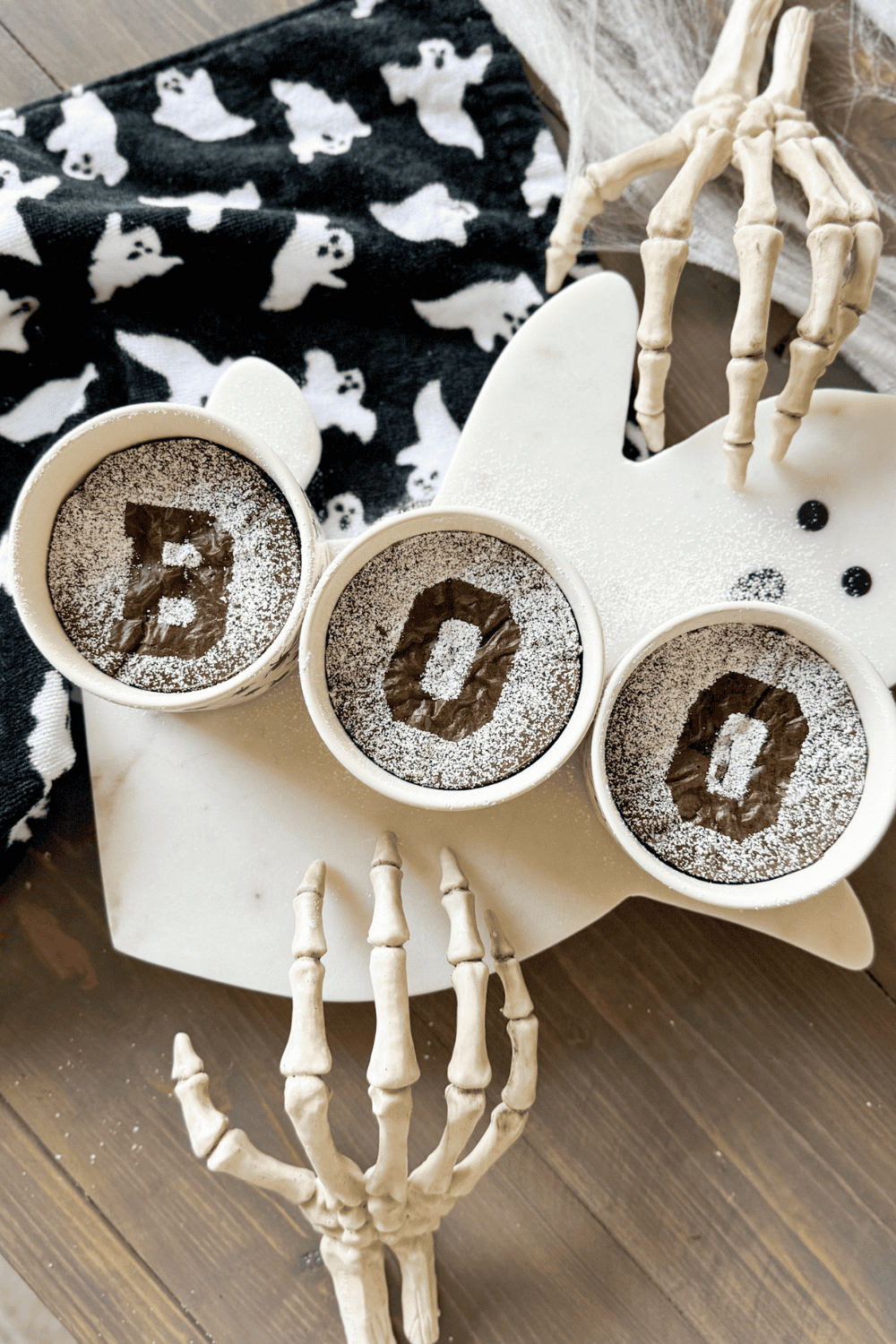 easy Halloween brownies with BOO design sitting on a ghost tray. Styled with Skelton hands and a ghost towel.