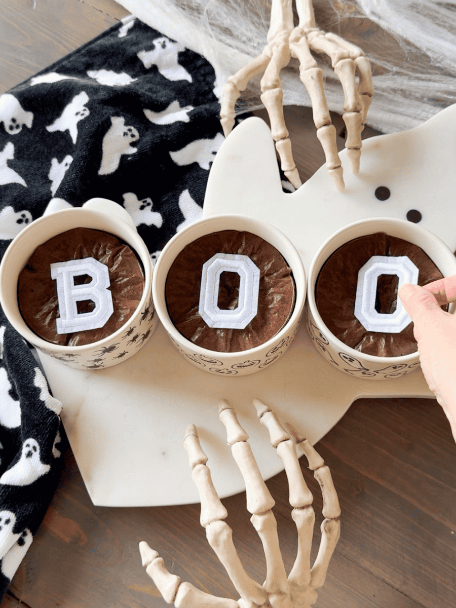 Easy halloween brownies with BOO design on ghost tray. Placing letters for stencil. Skeleton hands with ghost towel for added decor.