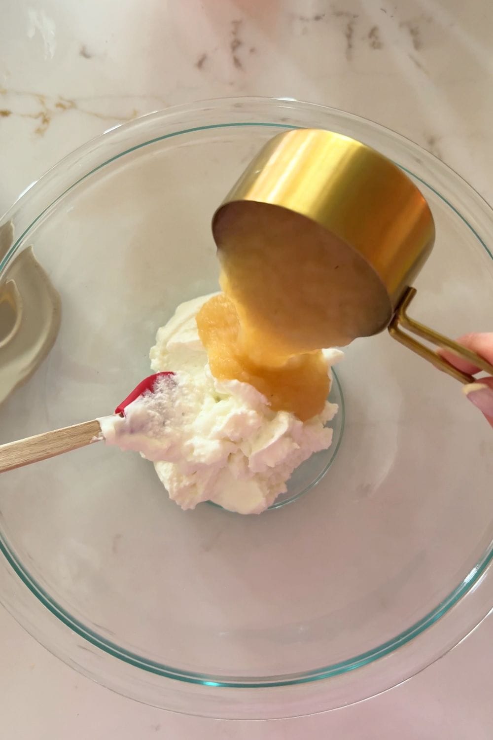 pouring applesauce into clear bowl with greek yogurt