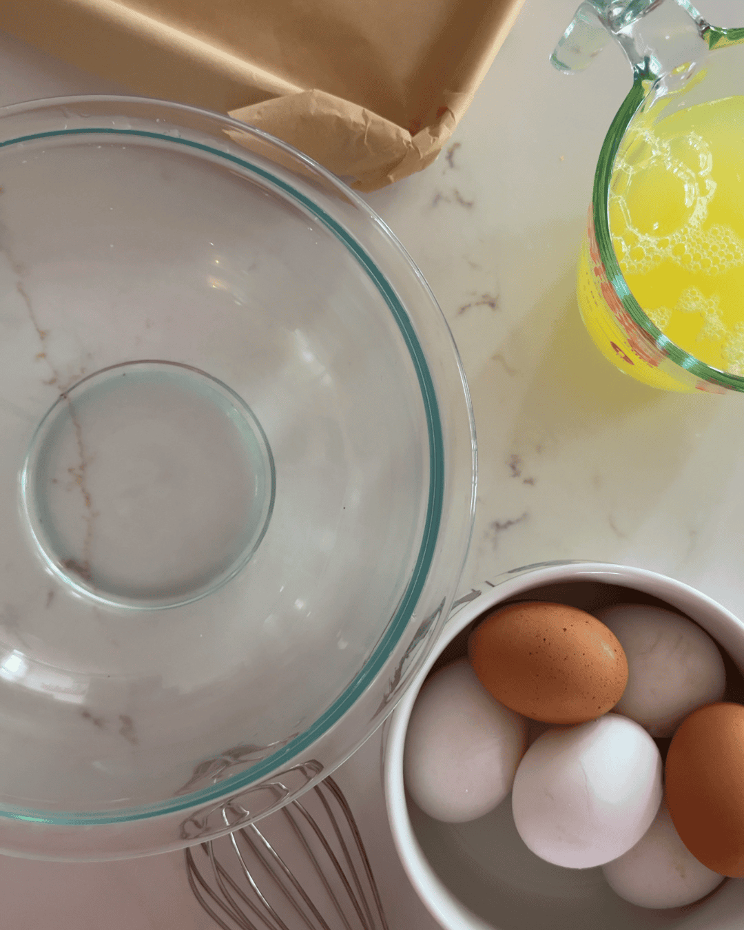 Eggs, liquid egg whites, and a parchment-lined sheet pan ready for breakfast sandwich meal prep