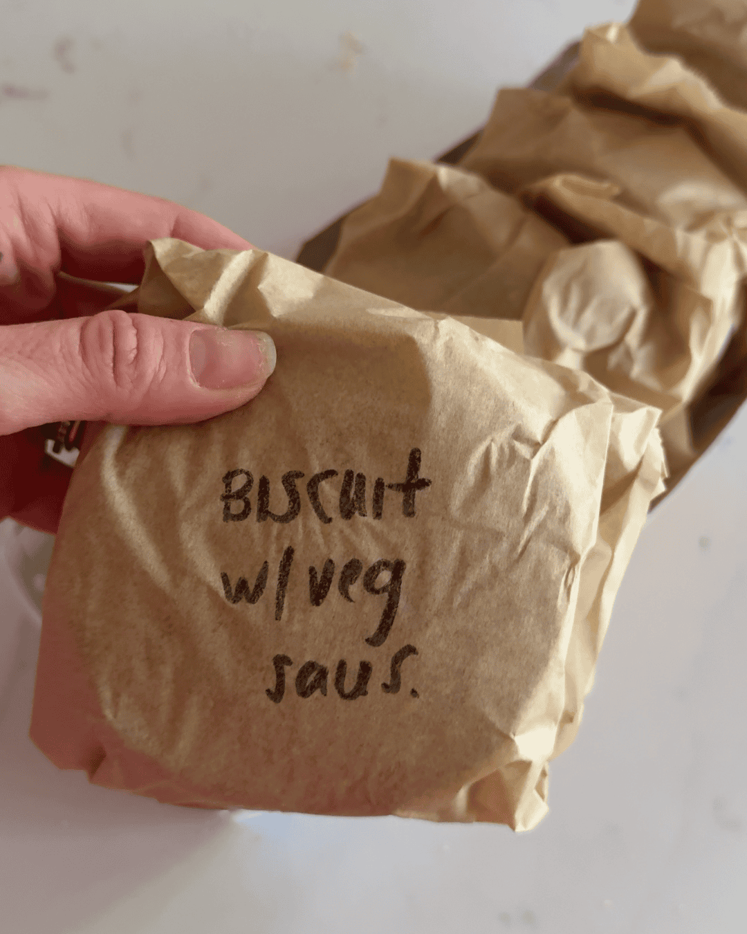 Parchment-wrapped freezer breakfast sandwiches stored in a container