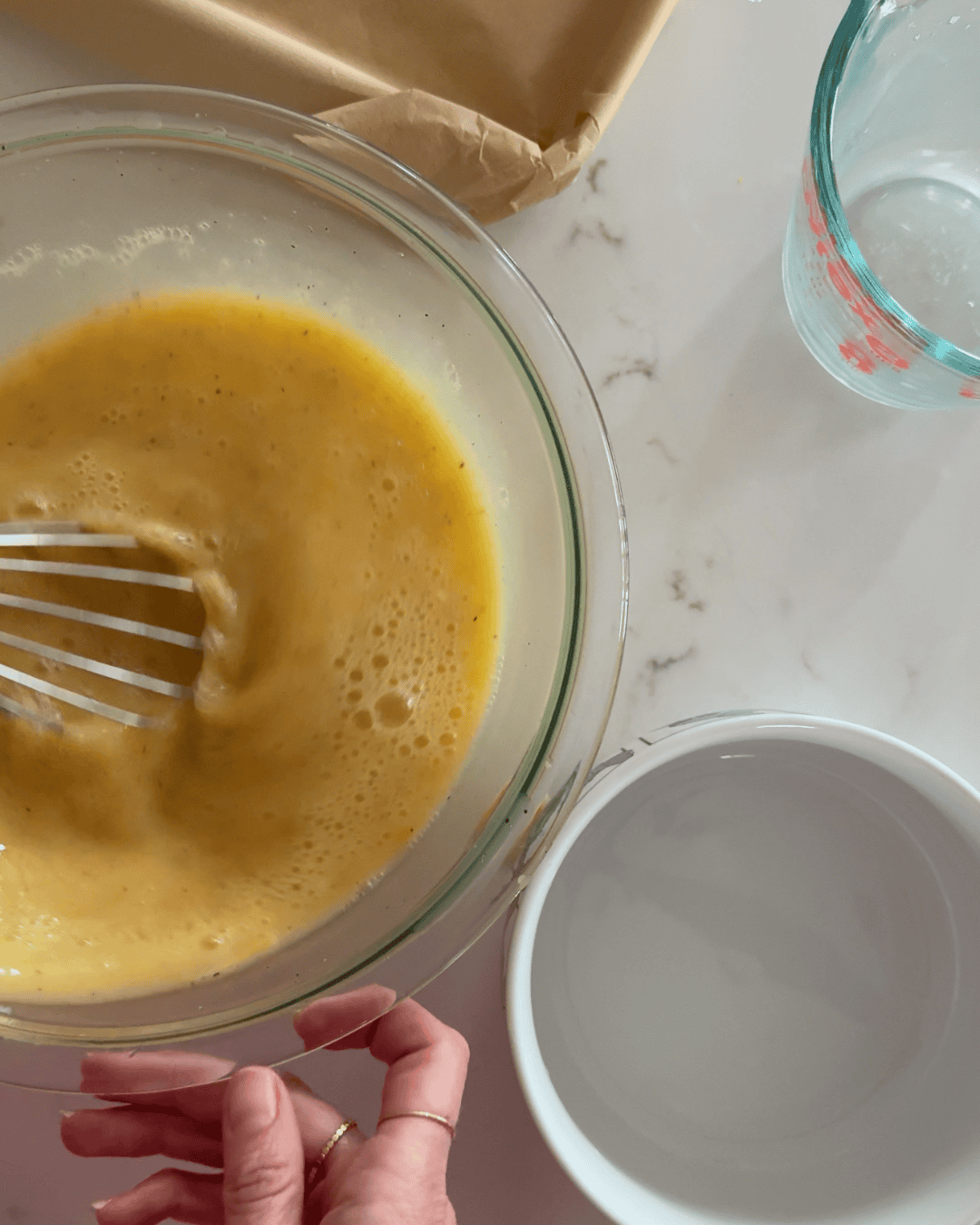 Whisking eggs, egg whites, and milk in a glass bowl for sheet pan eggs